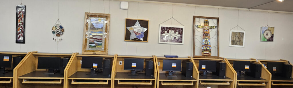 Art pieces hang on the wall above the computers in the library