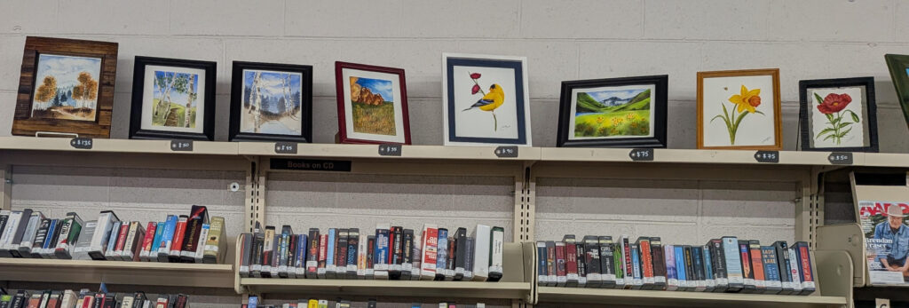 Watercolor art pieces in frames sitting on top of a shelf