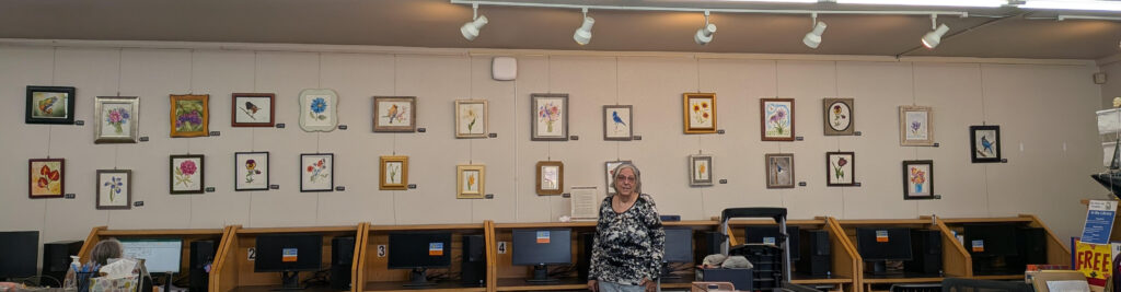Tracy Morgan, the artist, standing in front of the wall covered in her watercolor pictures.